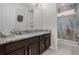 Bathroom with dual sinks, granite counters, and a tiled shower behind a glass enclosure at 1910 Donahue Dr, Ocoee, FL 34761