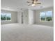 Bright, open bonus room with an ensuite bathroom, carpet, ceiling fan, and two large windows at 1910 Donahue Dr, Ocoee, FL 34761