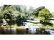 Picturesque lake view with dock, surrounded by mature trees and a lush green lawn at 2154 Lake Christie Dr, Orlando, FL 32809