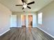 Bright bedroom with wood-look floors, ceiling fan, and ensuite bathroom and closet entrances at 216 Grove Branch Rd, Winter Haven, FL 33880