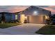 Single-story home's front exterior at dusk, featuring a two-car garage and illuminated landscaping at 2731 Rowan St, Tavares, FL 32778