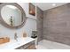 Bathroom featuring modern fixtures, decorative tile accent wall, and a round mirror at 3254 Oak Lake Pl # 137, Winter Park, FL 32792