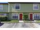 A two-story townhome with a red front door, surrounded by lush greenery and convenient parking at 3254 Oak Lake Pl # 137, Winter Park, FL 32792