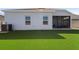 Home's backyard featuring artificial turf, rear exterior of the house and access to a screened in patio at 3532 Yarian Dr, Haines City, FL 33844
