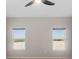 Sunlit bedroom with carpet, ceiling fan, and two windows showing the fenced backyard at 3532 Yarian Dr, Haines City, FL 33844