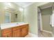Bathroom with a wooden vanity, white sink, green walls, and tiled shower at 3823 Martin St, Orlando, FL 32806