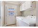 Bright laundry room with white washer and dryer, storage cabinets, and exterior door at 3823 Martin St, Orlando, FL 32806