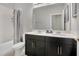 Modern bathroom featuring double sinks, sleek black cabinets, and a shower-tub combo at 4875 Lacewing Dr, Winter Garden, FL 34787