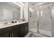 Bathroom featuring double sinks with black cabinets, glass enclosed shower with decorative tile and neutral wall paint at 4875 Lacewing Dr, Winter Garden, FL 34787