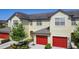 Exterior angle shot of tan townhomes with red garages, landscaping and covered entry at 509 Artisan St # 43, Orlando, FL 32824