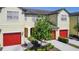 Exterior angle shot of tan townhomes with red garages, landscaping and covered entry at 509 Artisan St # 43, Orlando, FL 32824