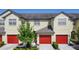 Exterior shot of a well-maintained townhome featuring red garage doors and lush landscaping at 509 Artisan St # 43, Orlando, FL 32824
