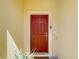Inviting red front door with a classic design, framed by a light-colored exterior and manicured plants at 509 Artisan St # 43, Orlando, FL 32824