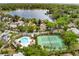 A scenic aerial view showcasing a community pool, tennis court, lake, and lush greenery in a charming neighborhood at 600 Fallsmead Cir, Longwood, FL 32750