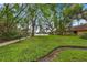 Landscaped backyard extending to the waterfront, surrounded by mature trees and well-maintained greenery at 600 Fallsmead Cir, Longwood, FL 32750