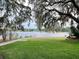 Beautiful waterfront backyard featuring mature trees, a pathway, and a glimpse of the tranquil water at 600 Fallsmead Cir, Longwood, FL 32750