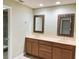 Well-lit bathroom featuring a double sink vanity, decorative mirrors, and a tiled shower at 600 Fallsmead Cir, Longwood, FL 32750