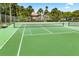 A vibrant green tennis court with a clear view of the net, enclosed by a fence and surrounded by palm trees at 600 Fallsmead Cir, Longwood, FL 32750