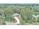 Aerial view of a red house with long driveway surrounded by green trees and a pond at 6144 Avenue G, Mc Intosh, FL 32664