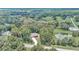 A scenic aerial view of a red home nestled amongst lush green trees with a pond nearby at 6144 Avenue G, Mc Intosh, FL 32664