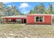 Inviting single-story home with a red exterior, lush plants and white trimmed windows at 6144 Avenue G, Mc Intosh, FL 32664