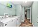 Well-lit laundry room with white washer, dryer, shelving, and durable wood-look flooring at 6144 Avenue G, Mc Intosh, FL 32664
