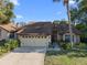 Inviting one-story home featuring a well-maintained lawn, mature trees, and a two-car garage at 7027 Villa Estelle Drive, Orlando, FL 32819