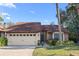 Charming single-story home with a two-car garage, manicured lawn, and mature landscaping at 7027 Villa Estelle Drive, Orlando, FL 32819