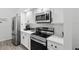 Modern kitchen featuring stainless steel appliances, white cabinetry, and quartz countertops at 7027 Villa Estelle Drive, Orlando, FL 32819