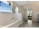 Bathroom with a large window, soaking tub, and glass enclosed shower at 7225 Nottingham Reel Ct, St Cloud, FL 34773