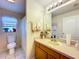 Well-lit bathroom featuring a vanity, toilet, shower with glass door, and window at 827 Princeton Dr, Clermont, FL 34711
