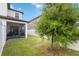 This backyard features a green lawn, a young tree and a privacy fence that surrounds the yard and a screen lanai at 8573 Lamppost Ln, Orlando, FL 32832