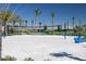 Outdoor sand volleyball court features a net, blue lounge chairs, and palm trees in this active community space at 8665 Theiler St, Orlando, FL 32827