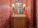 Bathroom featuring red marbled wall paper, framed mirror, sconce lighting, and wood vanity with sink at 1110 W Ivanhoe Blvd # 15, Orlando, FL 32804