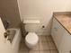 Cozy bathroom with tile floors, white toilet, tiled tub, and vanity with stone counters at 11574 Westwood Blvd # 1126, Orlando, FL 32821