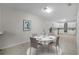 A dining area is set with a modern white table and chairs adjacent to a sleek, modern kitchen with white cabinets at 1210 S Clayton St, Mount Dora, FL 32757