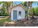 View of white outbuilding with a teal door and one window surrounded by palm trees at 1210 S Clayton St, Mount Dora, FL 32757