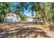 Wide shot of the property with a garage, house, and outbuilding surrounded by mature trees at 1210 S Clayton St, Mount Dora, FL 32757