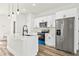 Modern kitchen with stainless steel appliances, white cabinets, island with black faucet and wooden floors at 14953 Sw 38Th Cir, Ocala, FL 34473