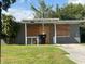A single-story home with a covered front entrance, gray cinderblock exterior and a lawn at 1515 20Th St, Orlando, FL 32805