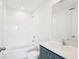 Well-lit bathroom featuring a shower-tub combo, blue vanity, and white-tiled walls at 15489 Hamlin Park Drive, Winter Garden, FL 34787