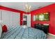 A cozy bedroom featuring bright red walls, modern decor, and a luxurious blue bed with plush linens at 1970 Summer Dr, Davenport, FL 33897