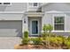 Charming home featuring a beautiful entryway with a blue front door, lush landscaping, and an attached garage at 1970 Summer Dr, Davenport, FL 33897