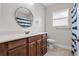 Clean bathroom with wood vanity, tile flooring, and shower-tub combination with a blue and white curtain at 216 S Holly Ave, Sanford, FL 32771