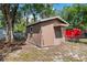A backyard shed with brown siding, a door, and a window, surrounded by greenery and a chain-link fence at 216 S Holly Ave, Sanford, FL 32771
