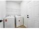 Bright laundry room features a washer, dryer, storage shelf, and door at 236 Marion Oaks Mnr, Ocala, FL 34473