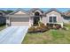 Charming single-story home featuring a two-car garage, brick walkway, and vibrant flower beds at 2977 White Cedar Cir, Kissimmee, FL 34741