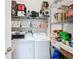 Laundry room with white washer and dryer, wire shelving with storage containers, and stocked with supplies at 2977 White Cedar Cir, Kissimmee, FL 34741