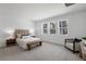 Serene bedroom with three windows, a tufted headboard, a cozy seating area, and neutral decor at 3532 Douglas Fir Dr, Apopka, FL 32703