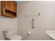 Compact bathroom featuring a toilet, pedestal sink, mirrored vanity, and safety bars at 3660 Ventura Club Cir, Orlando, FL 32822